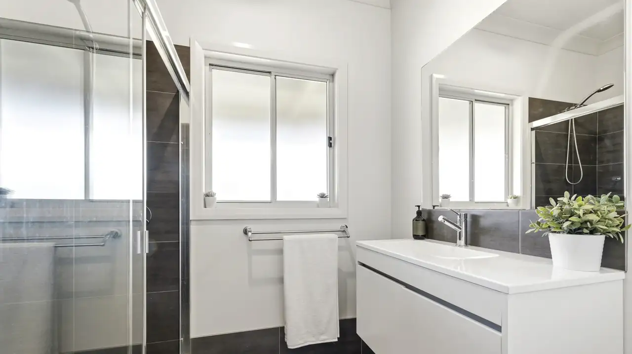 Bathroom with glass shower, charcoal tiles and a floating white vanity
