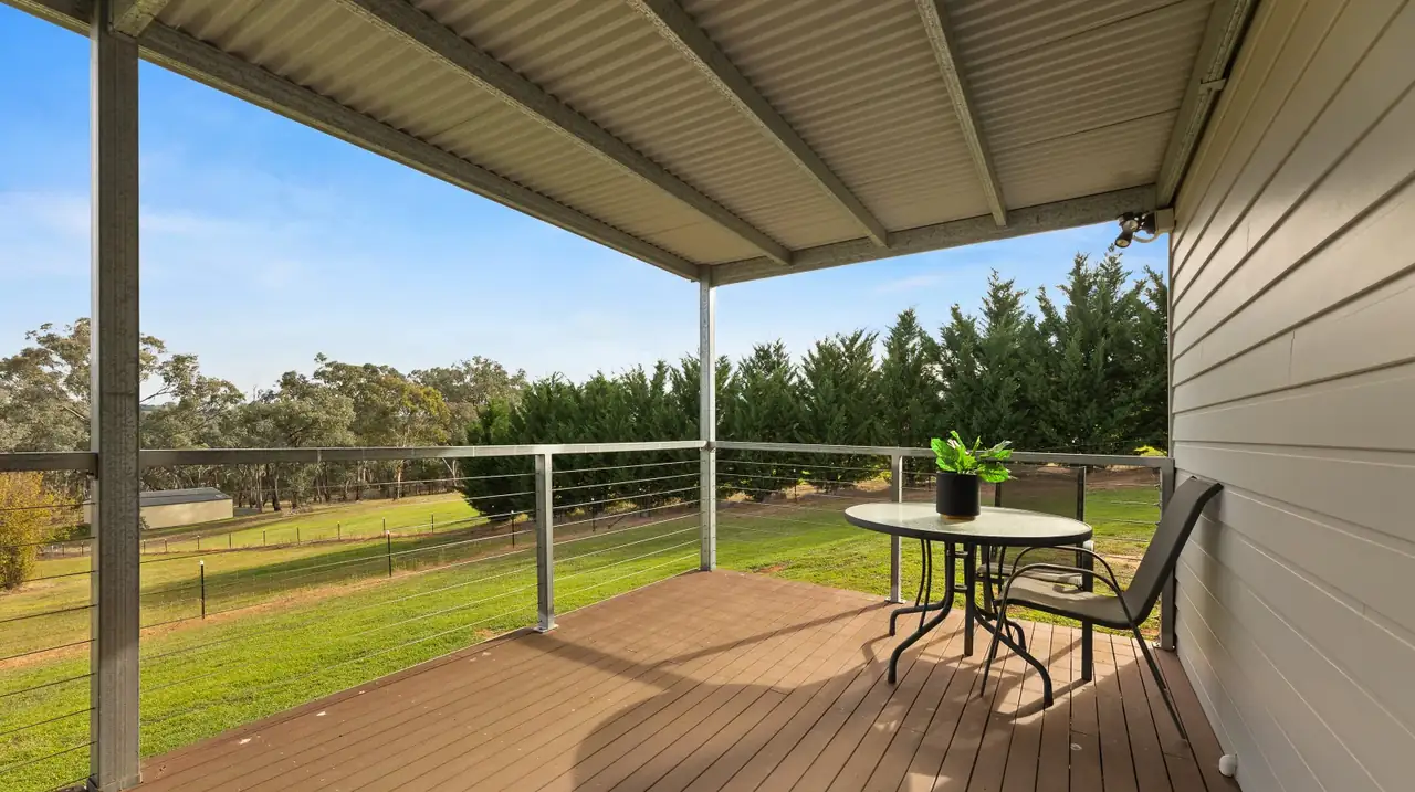 Corner of the deck with an outdoor table and chairs, cypress hedge beyond
